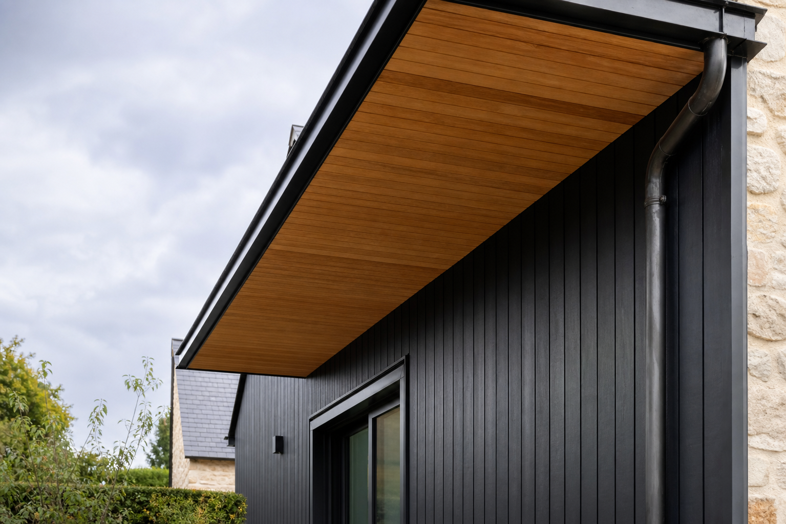 Bardage sombre et dessous de toit en bois sur une maison rénovée
